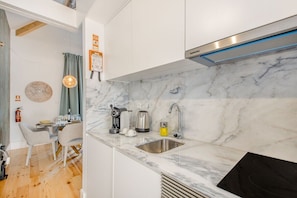 A modern kitchen with white cabinets, a marble backsplash, and a stainless steel sink. - Santa Catarina Charming Loft (Porto)