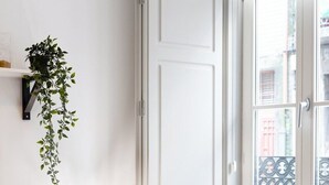 Ein Zimmer mit Fernseher, Pflanze, Lampe und Fenster mit Blick auf Gebäude.