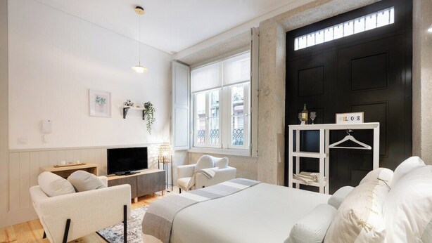 Ein modernes Schlafzimmer mit Bett, einer Couch, einem Fernseher und einem Kamin.