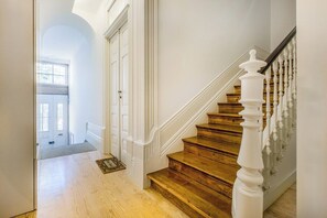 Eine Treppe mit Holzdielen und weißen Spindeln, die zu einer Tür mit weißem Rahmen führt.