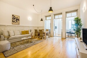 Ein Wohnzimmer mit einer Couch, einem Esstisch, Stühlen, einem Couchtisch und einem Fernseher.