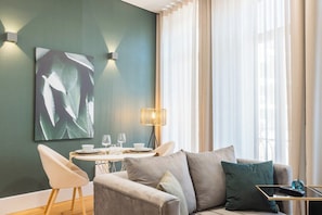 Ein modernes Wohnzimmer mit einer Couch, einem Esstisch und einem Bild an der Wand.