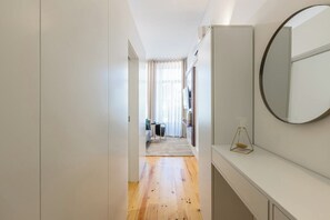 Ein schmaler Gang mit Holzboden, weißer Wand und rundem Spiegel.