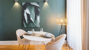 En matplats med ett runt bord, två vita stolar, en väggmonterad lampa och en golvlampa.