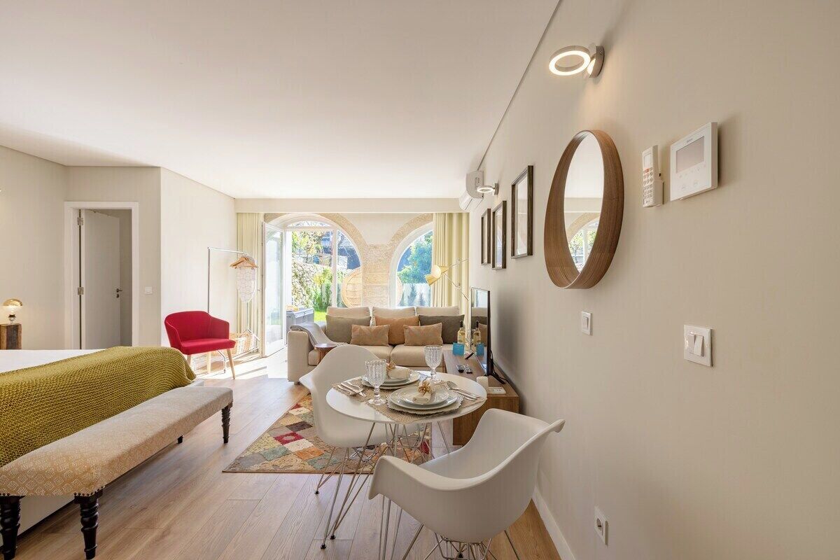 A modern living room with a dining area, a red chair, and a bench.