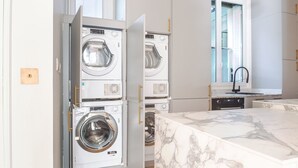 Una cocina moderna con electrodomésticos integrados, encimera de mármol y una ventana con persianas.