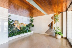 Ein modernes Interieur mit Holzboden, einer gefliesten Wand mit dekorativer Reliefstruktur und einem Blumentopf.