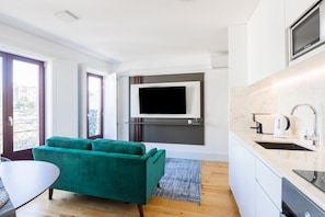 Eine moderne Küche mit Flachbildfernseher, einem grünen Sofa und einem Essbereich mit Tisch.
