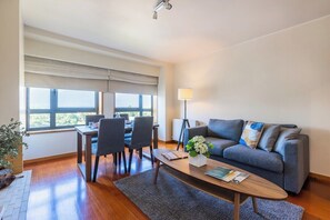 A modern living room with a sofa, coffee table, and dining area with chairs. - Foz Premium Retreat with Parking (Porto)