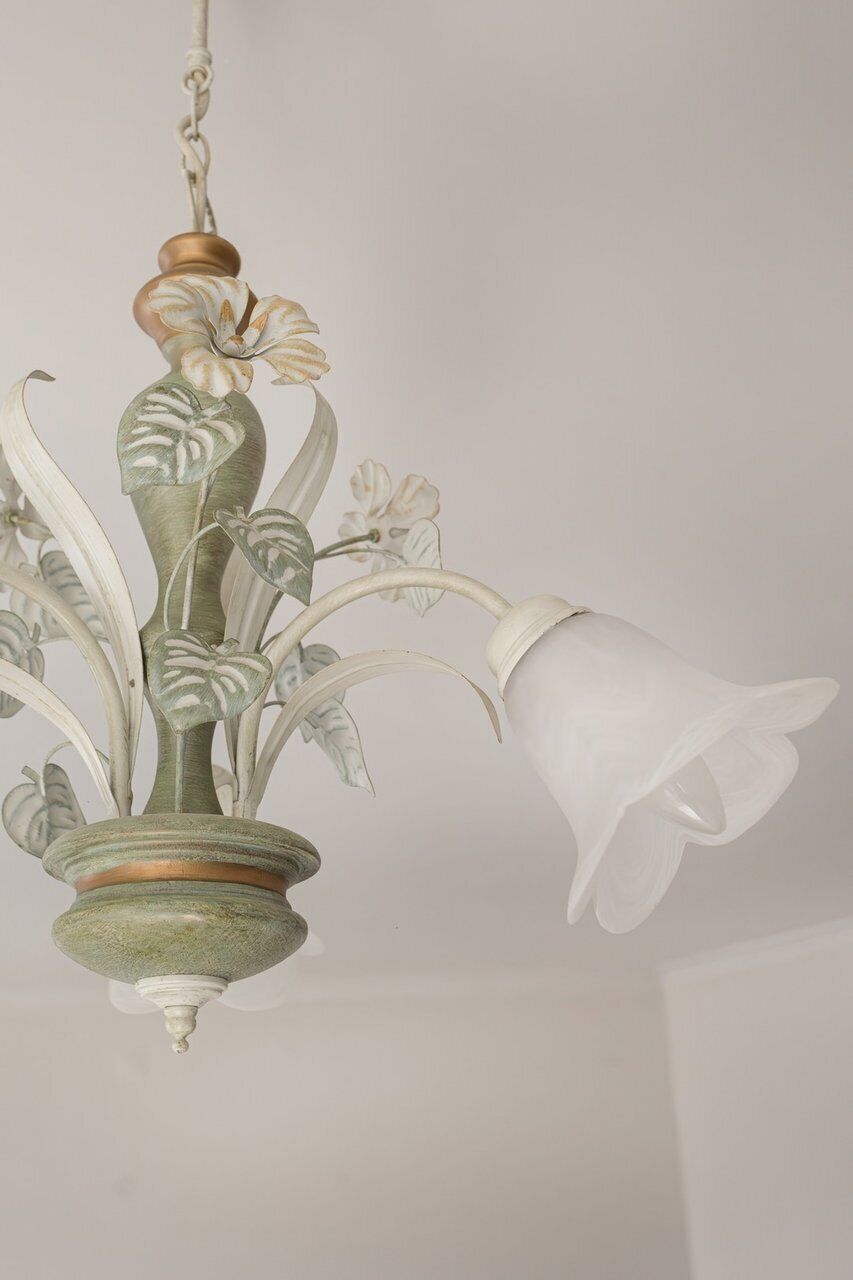 Ein Kronleuchter mit floralem Dekor und einem weißen Glaskolben.