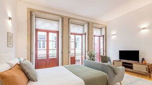 Une chambre avec un lit, une télévision et un balcon donnant sur une vue agréable.