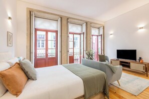 A bedroom with a bed, a TV, and a balcony view. - Sol Downtown Studio with Juliet Balcony (Porto)