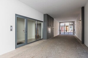 A corridor with a brick floor, a glass door entrance, and a metal gate at the end. - Bonfim Perfect Stays (Porto)