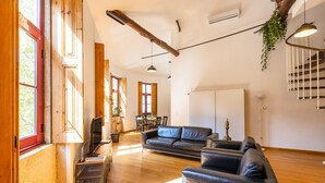 A spacious living area with a sofa, a TV, and a dining table. - Casa Fernando @ Trindade (Porto)