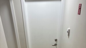 A white door with a silver handle, a patterned rug, and a wooden floor. - Cozy Urban Hideout (Saskatoon)