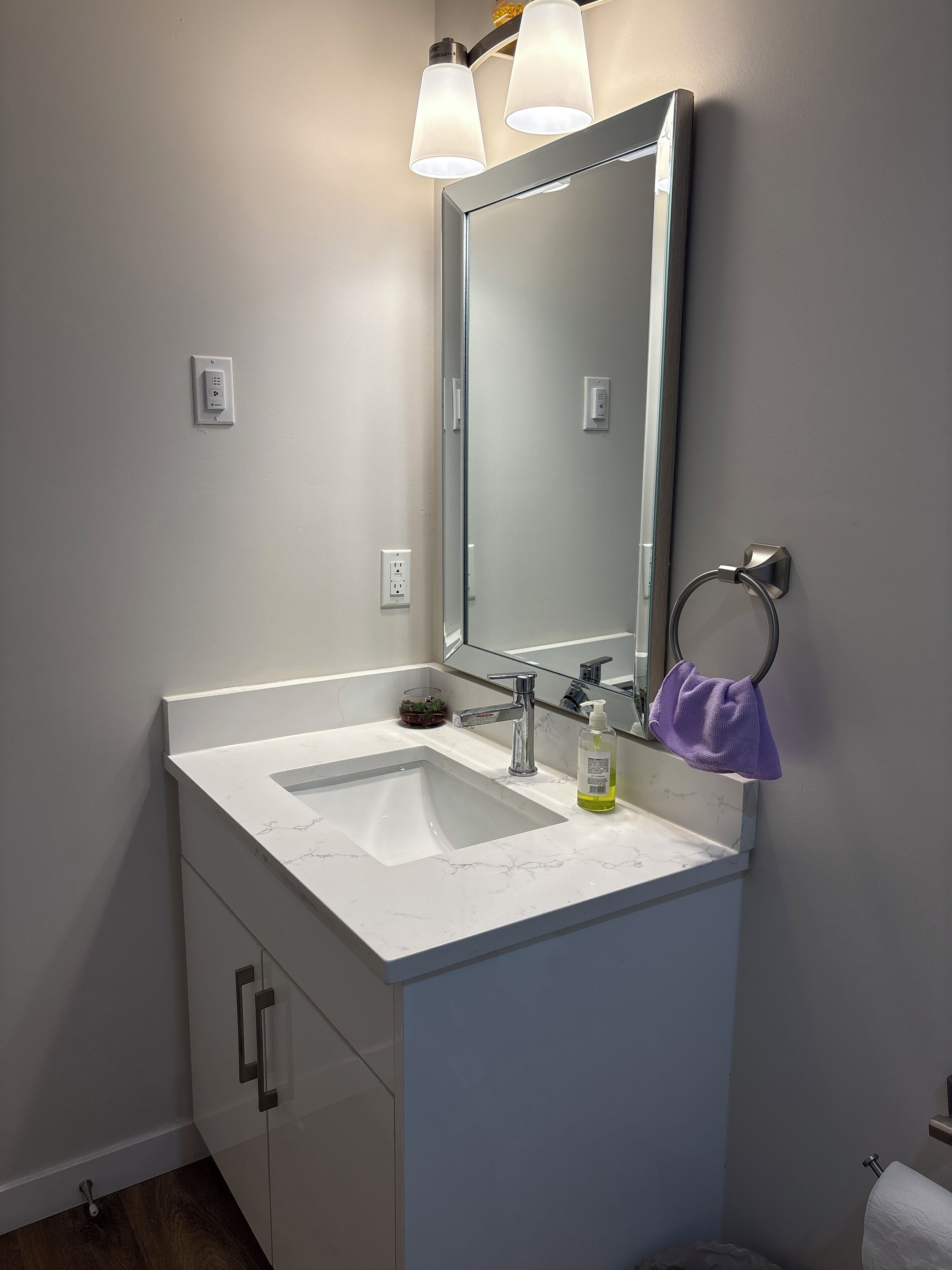 Un baño con tocador blanco, un espejo grande, un lavabo y un tocaderechos.