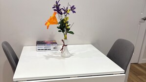 A white table with a vase of flowers and a book on it. - Cozy Urban Hideout (Saskatoon)