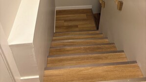 A wooden staircase with white walls and a wooden handrail. - Cozy Urban Hideout (Saskatoon)