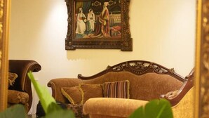 A room with a large mirror reflecting a painting, a brown sofa, and a chair. - Sahel Alma Luxurious 3 Bdrm With a Garden (Jounieh)