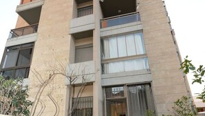 A multi-story building with a modern architectural design, featuring balconies and large windows. - Sahel Alma Luxurious 3 Bdrm With a Garden (Jounieh)