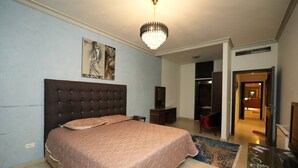 A bedroom with a large bed, a chandelier, a dresser, and a painting on the wall. - Sahel Alma Luxurious 3 Bdrm With a Garden (Jounieh)