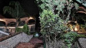 A stone staircase leading to a building with arched windows and a well-lit interior. - Suite vista hermosa  (San Miguel de Allende)