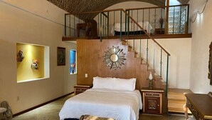 A bedroom with a large bed, a wooden headboard, a staircase, and a view of the outside. - Suite vista hermosa  (San Miguel de Allende)