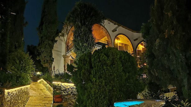 A nighttime view of a building with arched windows and a staircase leading to a pool area. - Suite vista hermosa  (San Miguel de Allende)