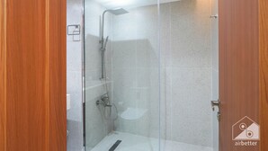 A glass-enclosed shower with a handheld showerhead and a wall-mounted faucet. - Vibrant Luxury Studio Emirates Gardens Dubai (Dubai)