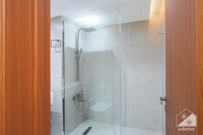 Eine Duschkabine mit Handbrause und am Wand montiertem Wasserhahn.