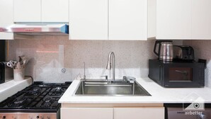 A kitchen with a stainless steel sink, a gas stove, a microwave, and a coffee maker. - Vibrant Luxury Studio Emirates Gardens Dubai (Dubai)