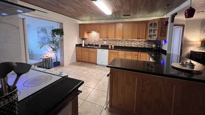 Una cocina moderna con armarios de madera, encimera negra y estufa a la vista.