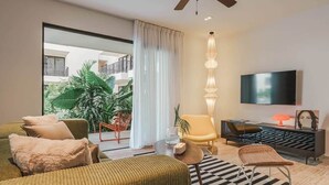 Een moderne woonkamer met een bank, fauteuils, een televisie en een balkon met planten.