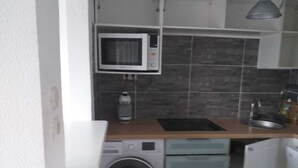 Eine kompakte Küche mit Mikrowelle, Waschmaschine und Spüle.