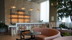 Un interior moderno con área de cocina, barra, asientos y plantas en macetas.