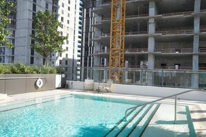A rooftop swimming pool with a view of a multi-story building under construction. - 2BR/2BA Palm Oasis at The Crosby (Miami)