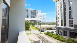 A modern building with a balcony overlooking a railway track and urban landscape. - 2BR/2BA Palm Oasis at The Crosby (Miami)