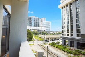 A modern building with a balcony overlooking a railway track and urban landscape. - 2BR/2BA Palm Oasis at The Crosby (Miami)