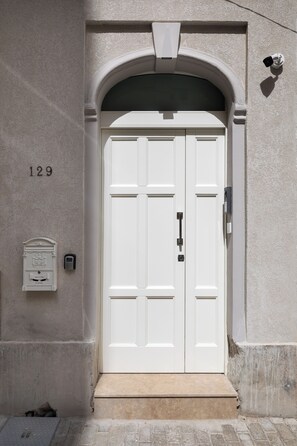 A white double door with a small step leading up to it, a mailbox, and a security camera on the wall. - Modern 1BD Maisonette & Private BackYard (Gzira)