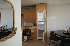 A compact kitchen with wooden cabinets, a built-in oven, and a refrigerator. - Stylish Minimalist 1BR in The Crosby (Miami)