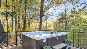 Ein Whirlpool auf einer Holzterrasse mit Blick auf einen Wald.