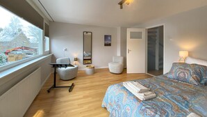 A bedroom with a bed, two chairs, a desk, a mirror, and a window with a view of a construction site. - 2 bedroom cozy apartment in Broek in Waterland (Broek in Waterland)