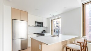 Une cuisine moderne avec des meubles blancs, un réfrigérateur en acier inoxydable, un four à micro-ondes et une cuisinière à gaz.
