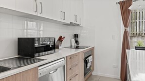 Uma cozinha moderna com armários brancos, micro-ondas embutido, lava-louças e um forno pequeno.