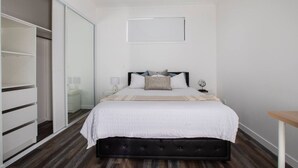 Ein Schlafzimmer mit Bett, Nachttischen, einem Spiegel und einem Kleiderschrank.