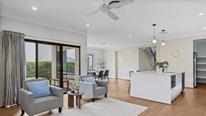 A modern living room with a sofa, a coffee table, and a kitchen island. - 3BR Family Home in Rochedale | Aussie Local Living (Rochedale)
