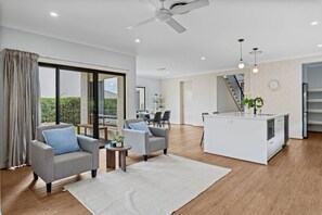 A modern living room with a sofa, a coffee table, and a kitchen island. - 3BR Family Home in Rochedale | Aussie Local Living (Rochedale)