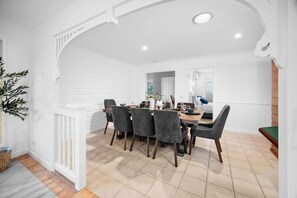 A dining area with a white interior, a wooden dining table, and grey upholstered chairs. - Modern 4B Family-Friendly Home in Robertson QLD (Robertson)