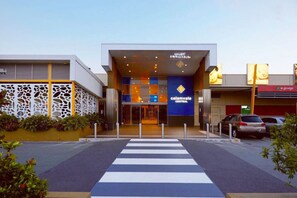 A modern building with a central entrance, a blue sign with 'calamvale central' text, and a crosswalk leading to the entrance. - Modern 4B Family-Friendly Home in Robertson QLD (Robertson)