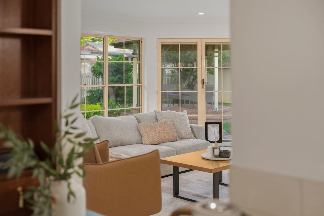 Un salon comprenant un canapé, une table basse et un fauteuil. De grandes fenêtres offrent une vue sur la verdure environnante.